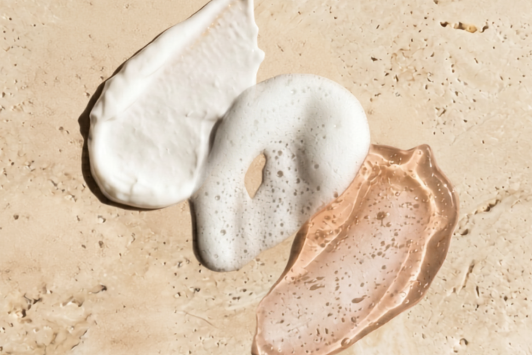 Textures du trio coiffant AIA Curls : crème, mousse et gelée coiffante sur fond de pierre naturelle